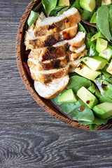 Green lunch bowl with grilled chicken, avocado and eggs. Healthy and dietary food. Space for text.