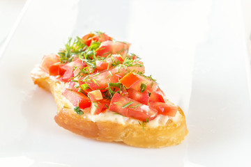 Bruschetta with fresh tomatoes and cheese on a white plate. Close-up