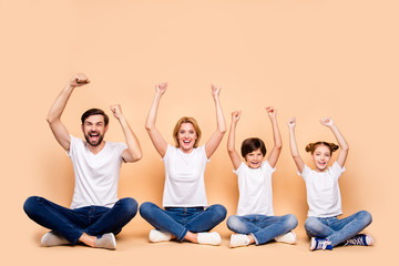Young smiling family, bearded father, blonde mother, little boy and girl wearing blue jeans and...