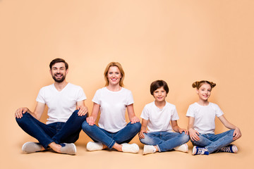 Young smiling family, bearded father, blonde mother, boy and girl wearing blue jeans and white...
