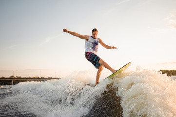 Young wakesurfer jumping on board riding down the river waves