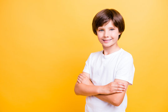 Portrait of attractive young school boy, smiling with folded crossed hands over yellow background, isolated. Copy space