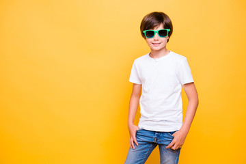 Portrait of attractive young cheerful school boy, smiling, wearing sun glasses standing over yellow...