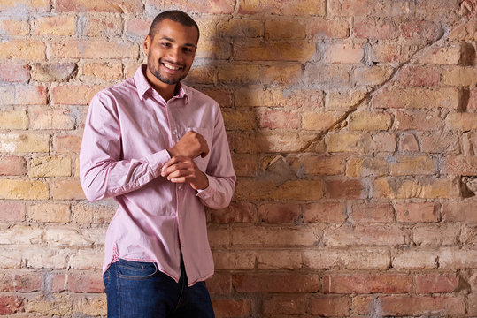 A Happy Handsome Young Man Buttoning His Pink Shirt.