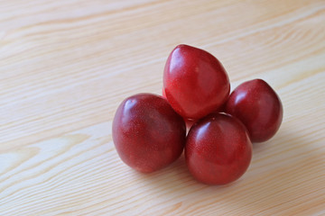 Many Fresh Gulf Ruby Plum Fruits Isolated on Natural Wooden Table 