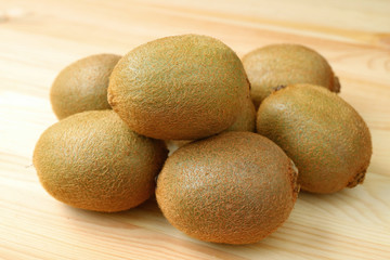 Pile of fresh kiwi fruits on the wooden table, with selective focus and blurred background 