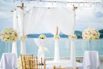 Close-up wedding arch and altar decorated with white soft lawn fabric and color roses flower...