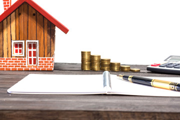 Financial planning concept empty house,notebook, pen, calculator and coin on wood table