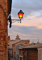 Empty street with golden light on sunset and old lamp in old city of Osimo, Marche Italy