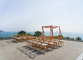 Modern wedding venue setting with wooden folding lawn chairs with sunny sky background