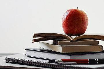Apple, pile of books and school supplies on the table on white background with copy space for text. Back to school and education concept