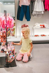 selective focus of adorable little kid choosing swimwear in shop