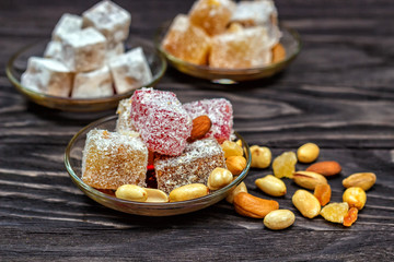 Traditional oriental sweets and traditional Turkish tea on a dark wooden background. Turkish desert-Rahat locum.