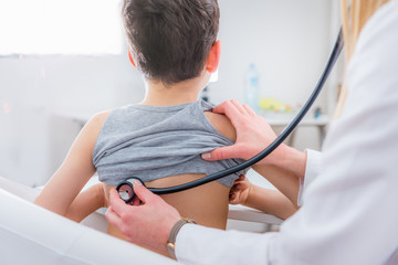 Pediatrician examining boy with stethoscope - obrazy, fototapety, plakaty