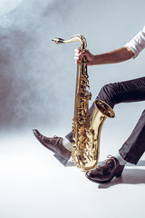 cropped shot of professional young musician holding saxophone on grey