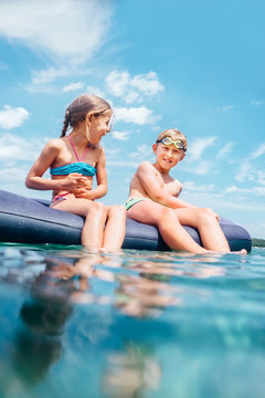 Happy smiling children, sister and brother, sit on inflatable raft