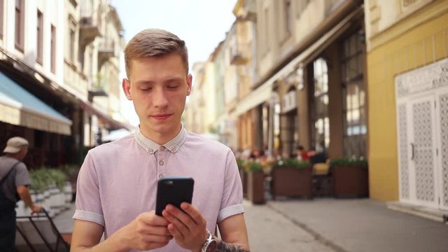 Portrait attractive young man use phone walk on street smile happy smartphone summer sun tourist adult business hipster caucasian cell office messaging slow motion