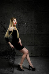 young girl in the studio; tall and beautiful girl with big eyes; 
model looks girl poses; 
model with long hair;
brown-haired European model; on a dark background near an iron chair
