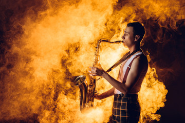 side view of expressive stylish young jazzman playing saxophone in smoke