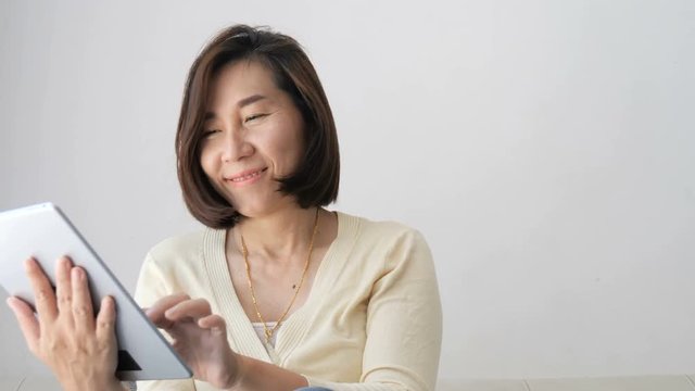Asian woman relaxing on sofa using laptop near window at home. 