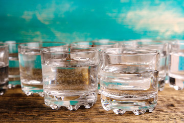 a lot of shots filled with vodka on a wooden table