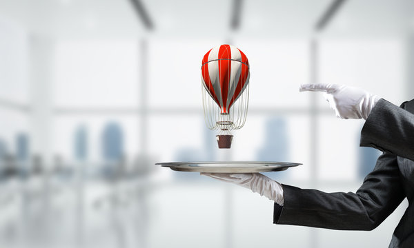 Hand of waiter presenting balloon on tray.