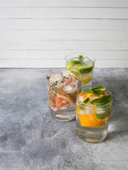 Set summer cold drinks with different citrus in glasses on a gray background. Cocktail with grapefruit, orange, lemon lime and ice Refreshing diet drink.