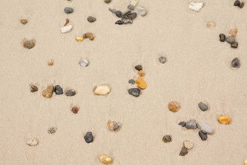 Fototapeta na wymiar Top view of colorful stones on sand at the beach.