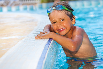 Smiling boy standing in water of swimming pool