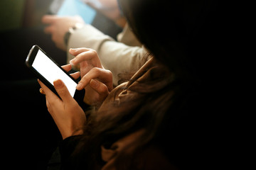 stylish woman holding phone and touching empty white screen, sitting at meeting, business marketing lecture