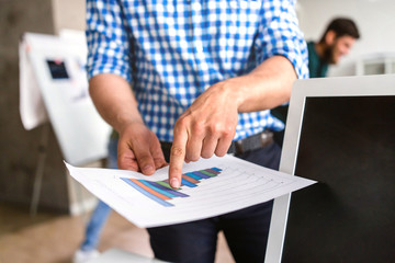 Businessman in checkered shirt in the office is pointing the finger at schedule of revenues closeup