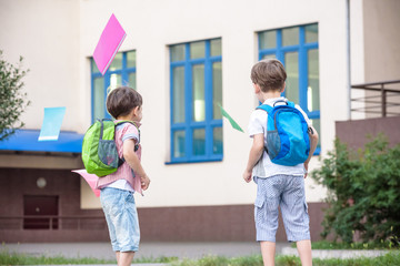 Happy children - two boys friends with books and backpacks on the first or last school day.