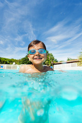 Cute boy enjoying summer, swimming in the pool