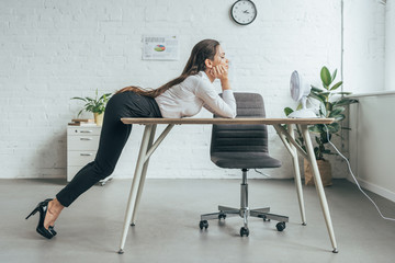 businesswoman conditioning air with electric fan at workplace in office