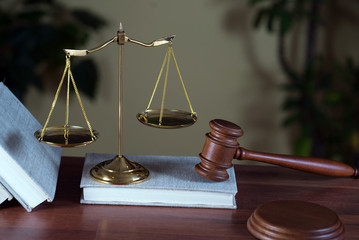 Lawyers office room with the scales of justice, hammer and old law books in the background