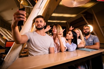 Friends at the bar take selfies on the phone sitting at the bar