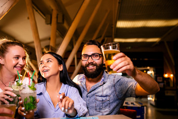 Funny friends drink beer at the bar