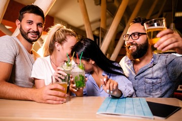 Friends at a party in a night bar drinking alcoholic beverages