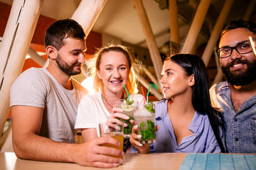 Friends at a party at the bar drinking alcoholic beverages communicating with each other