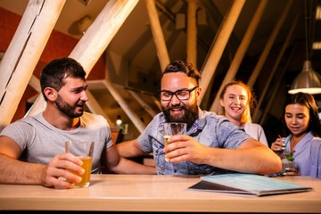 Two men drink beer in a nightclub on the background of girls