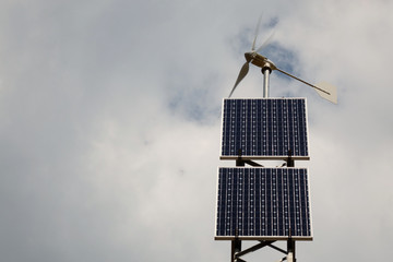 Solar panel and wind turbine on the sky background .