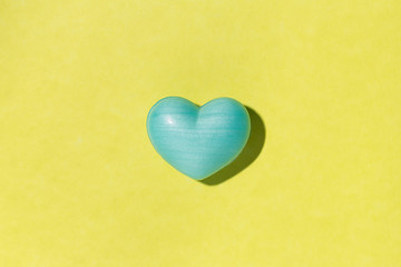 Blue heart shape over yellow table. Valentines day symbol for background use. Love, romance, and passion.