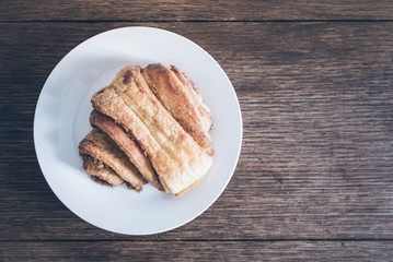 top view of Franzbrötchen pastry on plate on rustic wooden table. Franzbrötchen are a sweet cinnamon pastry and a local delicacy in and around Hamburg, Germany.