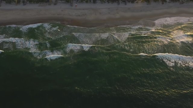A Phantom 4 Drone pulls away from the beach and houses in the city of Corolla at the Outer Banks during sunset from several hundred feet above the water.