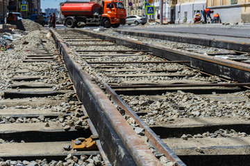 Laying of new steel rails on wooden sleepers in a prepared mound of large crushed stone for new tram lines in the city center