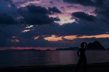 Fototapeta premium Lady in silhouette do yoga with Twilight sky colorful and cloudy over the beach on background