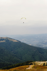 parachute skydiver flying in clouds at mountains, travel adventure concept, space for text