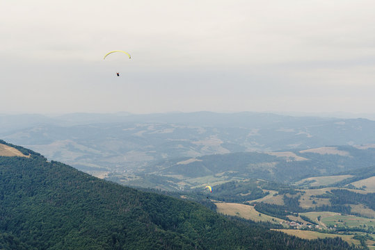 parachute skydiver flying in clouds at top of mountains with amazing view, travel adventure concept, space for text