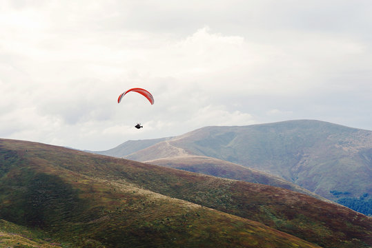 parachute skydiver flying in clouds at mountains, travel adventure concept, space for text