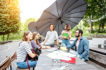 Young friends having fun talking together during a studying outdoors in the park